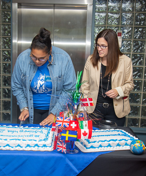Amaris T. Smith, culinary arts and systems, cuts the cake while Kathleen V. McNaul, director of college transitions and first year initiatives, looks on.