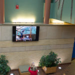 A guest snaps a cellphone photo of the work-in-progress, shown on one of the atrium’s monitors.