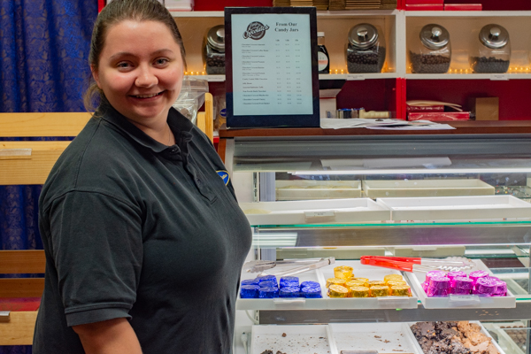 Taylor D. Lang, a May graduate in early childhood education, proudly stands at the family-owned Lang's Chocolates – among the downtown businesses offering a student discount.