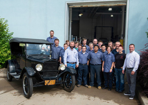 Aubrey Alexander (front row, left) and brother Adam (front row, right) deliver a 1926 Ford Model T to students and faculty outside College Avenue Labs, home to Penn College’s automotive restoration and collision repair majors.