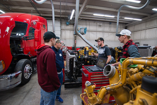 Diesel technology students Eric M. Sander (far right), of Williamsport, and Cody S. Fink (second fom right), of Lenhartsville, engages a son and father in technical banter. 