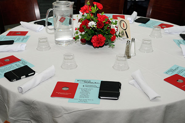 Elegant table settings include a Madigan Library bookmark, cast list and a notebook in which to record clues from the crime scene.