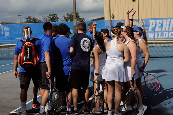 The Wildcat men's and women's tennis team huddle in solidarity before their Sunday match against King's College.
