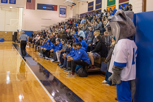 The college mascot “stands guard” during the opening game, as the men's squad awaits its turn on the court.