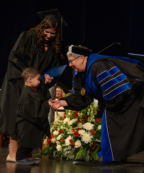 Nursing grad Rachel J. Cressman is upstaged by her son during their moment with President Gilmour.
