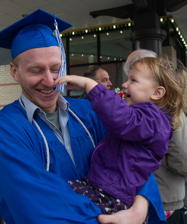 Timothy W. Brooks laughs with his daughter as she delightedly plays with his graduate tassel. Brooks, of Trout Run, graduated in building construction technology.