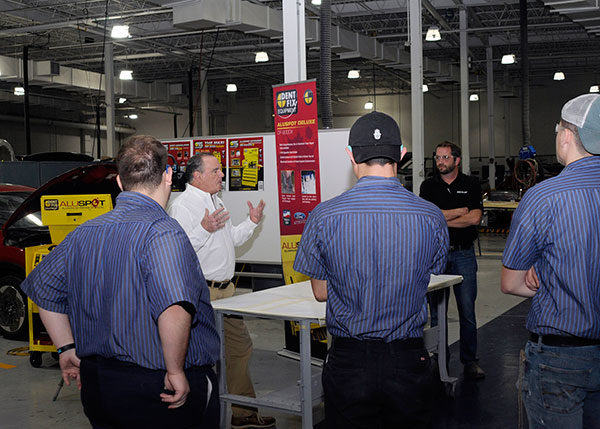 Penn College students and collision repair instructor Shaun D. Hack (in black shirt) listen as Daniel L. Maloney Jr., national sales director for Dent Fix Equipment and a member of the college’s Collision Repair Advisory Committee, demonstrates a donated aluminum dent-repair station.