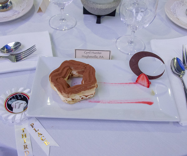Cyril L. Hunter’s pate a choux (French for cream puff dough or choux pastry) star, filled with vanilla diplomat cream and paired with a brush of strawberry and kiwi coulis and a dark-chocolate crescent moon, earns third place.