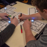 High school students draw paths for their Ozobots.