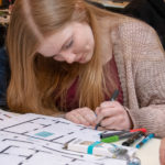 A high-schooler draws multicolor paths to direct her color-sensing Ozobot.