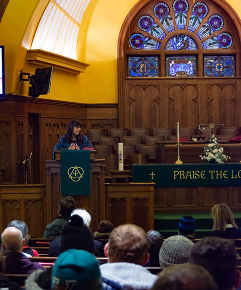The Beloved Community Council's Mary Woods emcees the musical program.