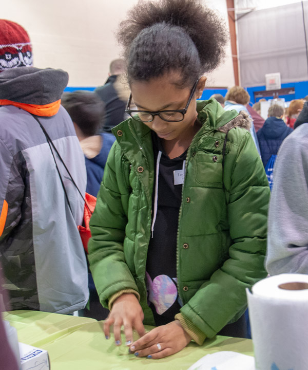 A child from the Loyalsock Township School District mixes a polymer – a slime that participants took home as souvenirs – thanks to the Society of Plastics Engineers PlastiVan.