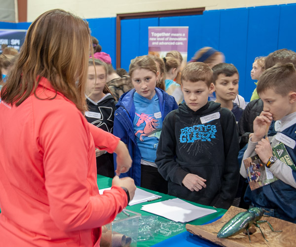 Children from East Lycoming School District watch and ask questions as a cockroach crawls around the hand of a demonstrator from Penn State Extension.