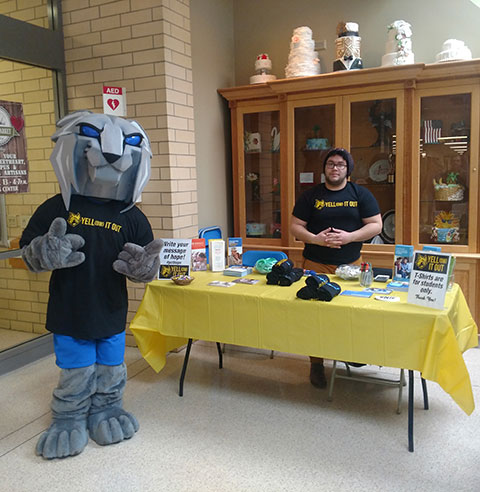 Civil engineering technology major and student leader Alexis J. Medero, staffing a table outside the Keystone Dining Room, is visited by a supportive college mascot.