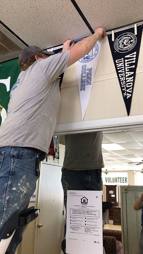 Saylor hangs a college pennant in the store, a tradition that Habitat officials equate to cutting down the net after a basketball tournament.