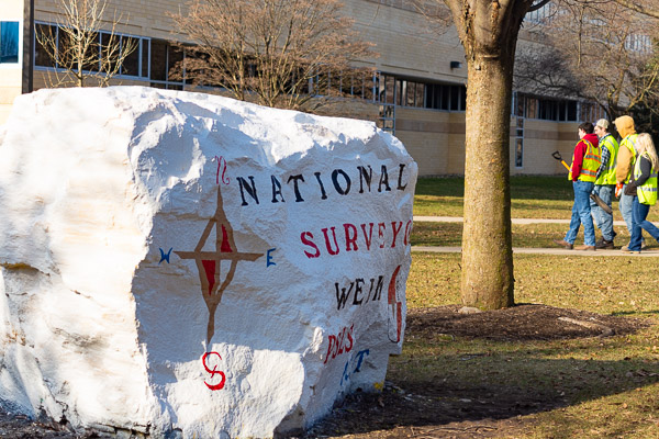 Members of the Penn College PSLS chapter get hands-on experience on campus, within the shadow of the rock they painted for Surveyors Week. (Photo by Rachel A. Eirmann, student photographer)