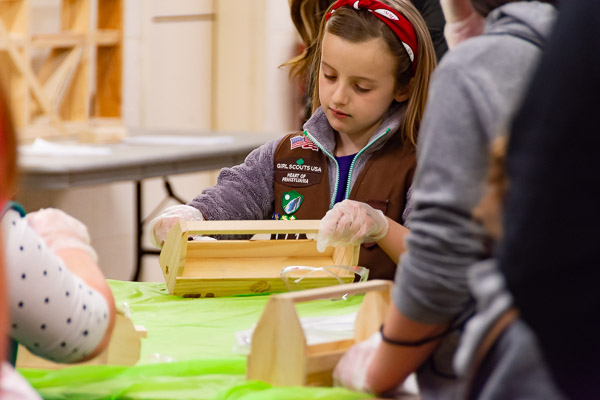 A Brownie, exploring the world of carpentry and woodworking, gets started on her toolbox. Daisy and Brownie activities were facilitated by the Women in Construction student organization.