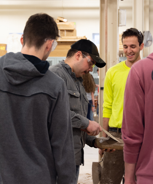 Penn College students Nathaniel M. Barbolish (in cap) and Joseph F. DiBucci (in yellow) demonstrate buttering and furrowing techniques. Barbolish, of Nicholson, is enrolled in residential construction technology and management: building construction technology concentration, and DiBucci, of Glenshaw,  is an applied technology major.