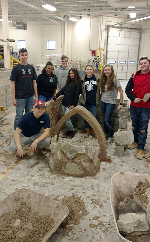 Visiting students gather round an arch they created.