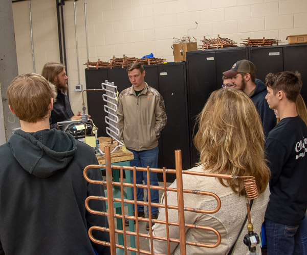 Daniel J. Harris, instructor of HVAC technology, talks with a group about classes in air conditioning and refrigeration while showing them a lab.