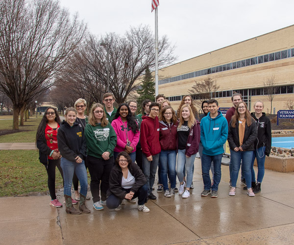A group pauses for a photo between a tour in the Advanced Technology & Health Sciences Center and their waiting school bus.
