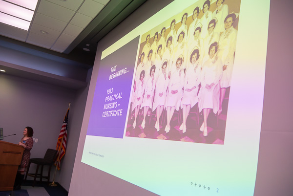 A photo from WTI's 1963 entry into nursing education is projected while Val A. Myers, assistant dean of nursing, balances yesterday's beginnings with current technologies.