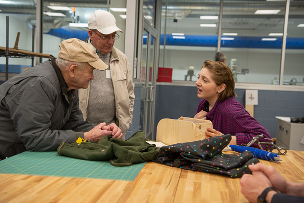 In the makerspace, Davies “talks shop” with William Olson (left), ’58, carpentry, and Ronald Good, ’67, draftsman-mechanical. Olson was impressed with Davies’ woodworking skills. 