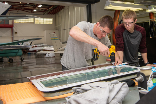 A Cessna 172 door hinge is the focus for Raymond E. Konikowski Jr. (left), aviation maintenance technology, and Brendan L. Kressler, aviation technology. 