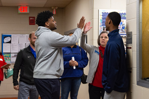 A multitasking Tammy M. Rich, assistant professor of business administration/management/event management, talks earnestly with one business/basketball prospect while high-fiving another.