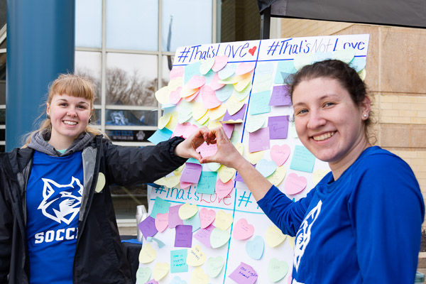 Soccer teammates Charlee R. Marshall (left), of Snow Shoe, and Madison L. Kistler, of Kutztown, promote an interactive display of sticky notes listing what love is – and isn't.