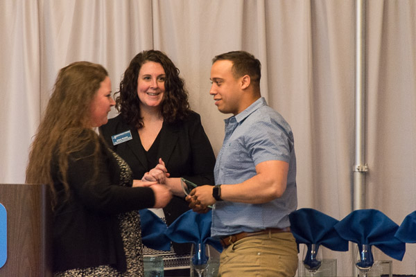 Representing the veterans fraternity, automotive student Andrew Placencia accepts one of the group's numerous awards from Sammie L. Davis (left), coordinator of diversity and cultural life, and Allison A. Bressler, associate director of student activities for new student program leadership.