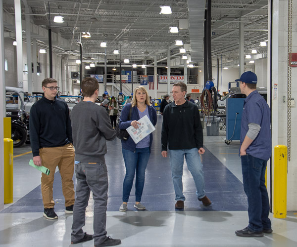 A pair of students guides a family through the college’s impressive collision repair facilities.
