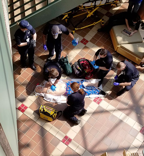 Paramedic students work through an emergency scenario in the ATHS atrium, treating a manikin so lifelike it drew double takes when transported down the campus mall!