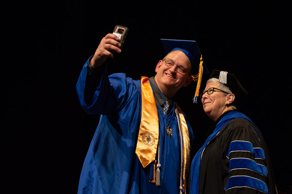 Mark A. Fink, graduating with high honors in heating, ventilation and air conditioning technology, snaps a selfie with President Gilmour. (“Never too old to get it done!” his cap read.)