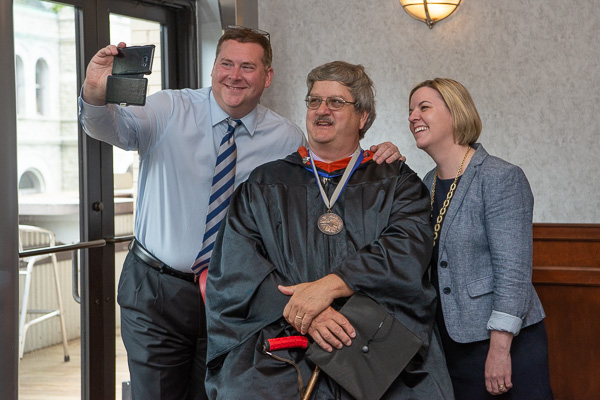 Retiring faculty member Chef Paul E. Mach (center), assistant professor of culinary arts, enjoys a selfie-made moment with Elliott Strickland Jr., vice president for student affairs, and Carolyn R. Strickland, vice president for enrollment management/associate provost, in the Capitol Lounge prior to the Saturday afternoon commencement.