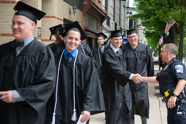 A regular on the commencement scene, Penn College Police Officer Charles O’Brien shakes hands with graduates as they proceed into the graduation venue.  