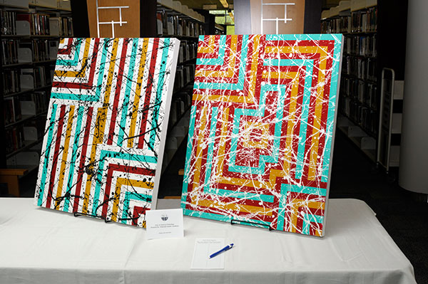 Student creations, such as this pair of abstract paintings by manufacturing engineering technology major Dakotah G. Snyder, filled the tables.