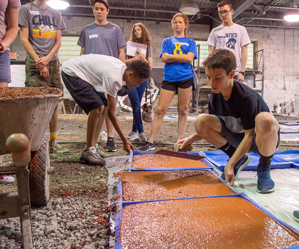 Led by Franklin H. Reber, instructor of building construction technology, and students, Career Day visitors create concrete stepping stones.