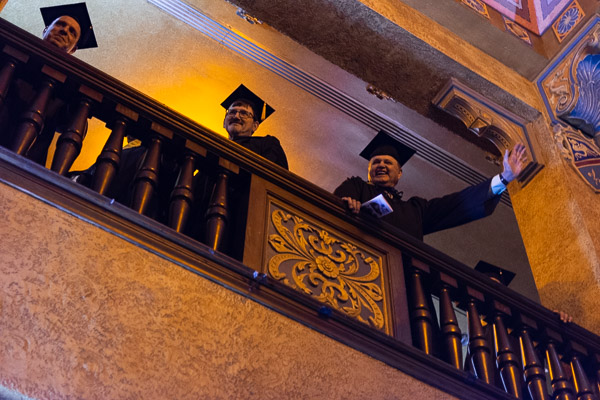 Faculty wave from upstairs as the processing students enter the theater.