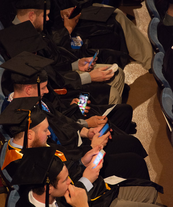 Graduates follow the instructions of Maize, Friday's student speaker, who encouraged them to immediately send a text to someone they wanted to thank.