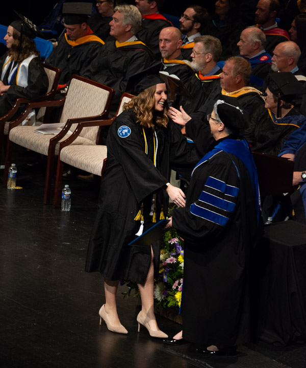 Cum laude graduate Erin N. Shaffer – graphic designer, student-athlete and international traveler – pauses with the president.<br />
