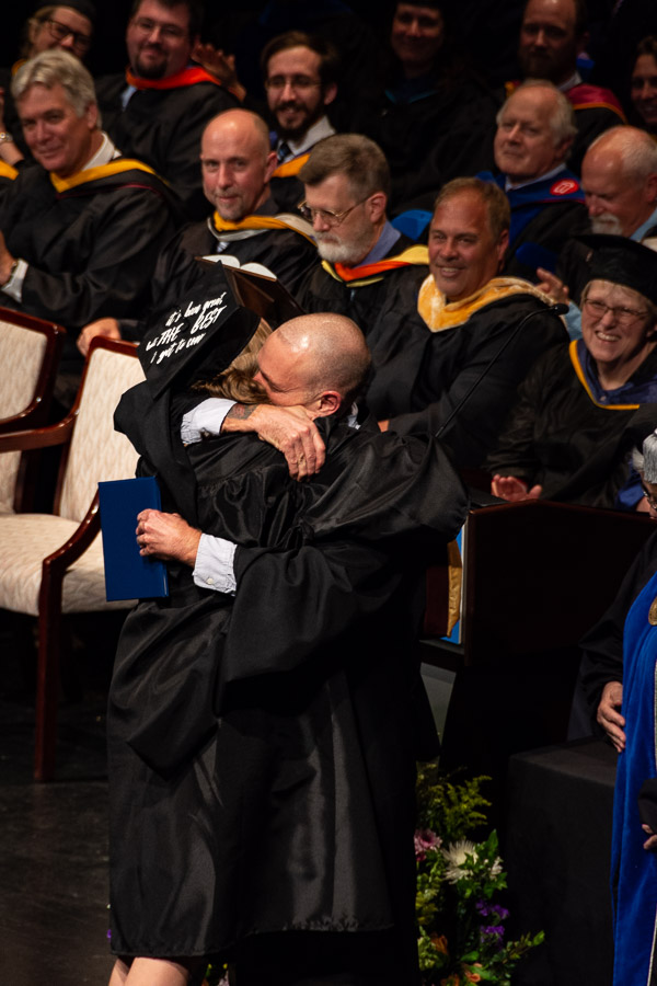 Friday's student speaker is jubilantly hugged by her father, speech communication/composition instructor John D. Maize after she received her diploma from the president.