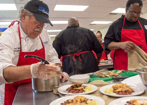 Ditchfield adds sauce to the blue team’s entrée. At right is team member Chef Ron Taylor, of Diamond Street Christian Church.