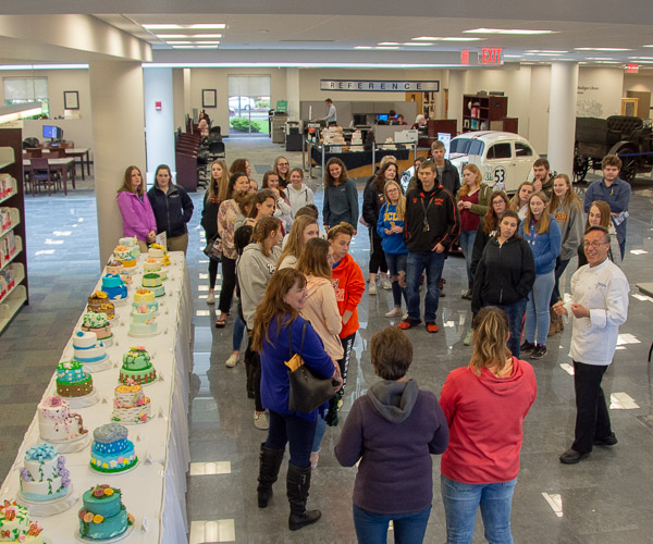 A group learns more about students’ final assignment in Cakes and Decorations from Chef Craig A. Cian, associate professor of hospitality management/culinary arts.