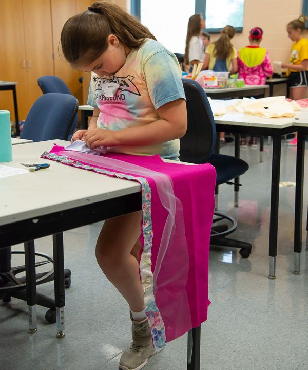 A young camper focuses on creating a pocket on a skirt in the wearable art workshop of Creative Art Camp.