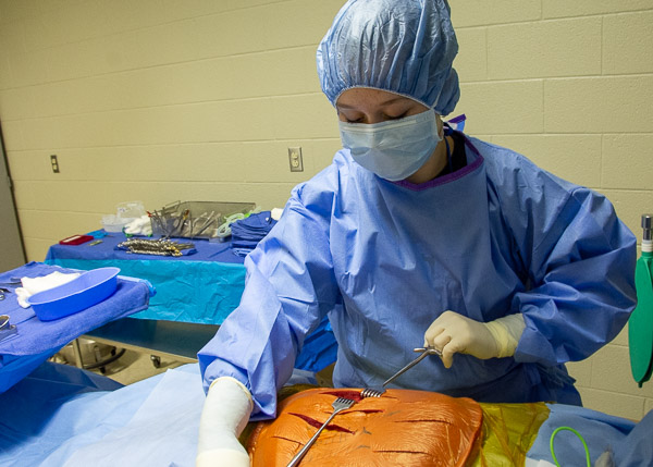 A visitor practices using retractors in the surgical technology lab’s operating room.