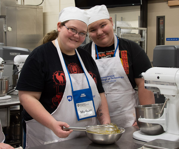 In the baking lab, visiting teens pause from whisking the ingredients for crème brulee.