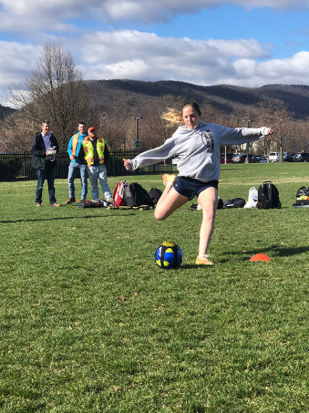 About to blast an instrumented ball is Kayla M. Spotts, of Shamokin, among the Wildcat soccer players cooperating in an exercise with civil engineering and surveying students at Penn College.