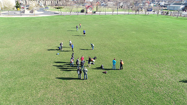 Civil engineering technology students start to lay out the Soccer Ball Experiment while student-athletes warm up.
