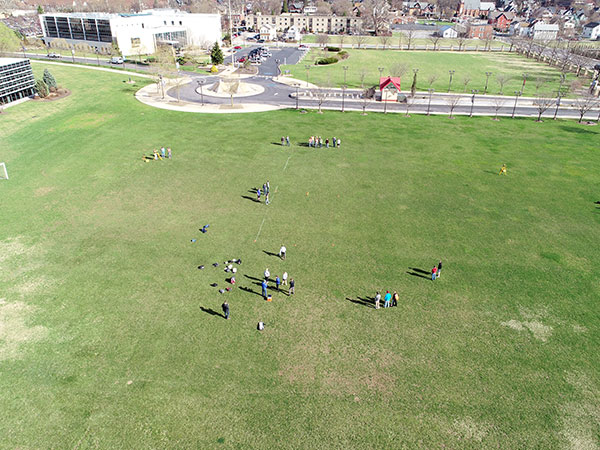 A view of the experiment from the perspective of a drone. (Total stations are positioned to the far left and far right of the landing area, and surveying technology students with GPS rovers waiting at top center of the photo.)